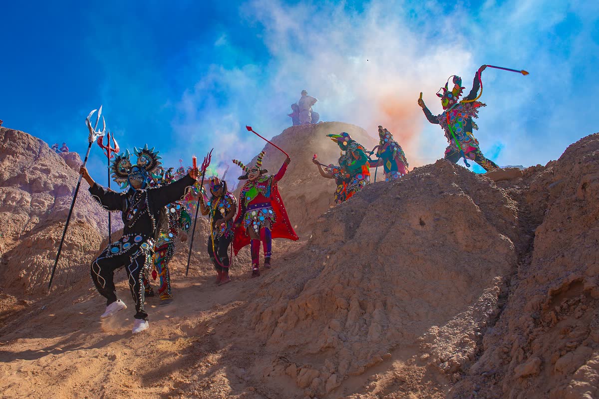 Diablos de carnaval bajando del cerro entre humo de colores, en Maimará