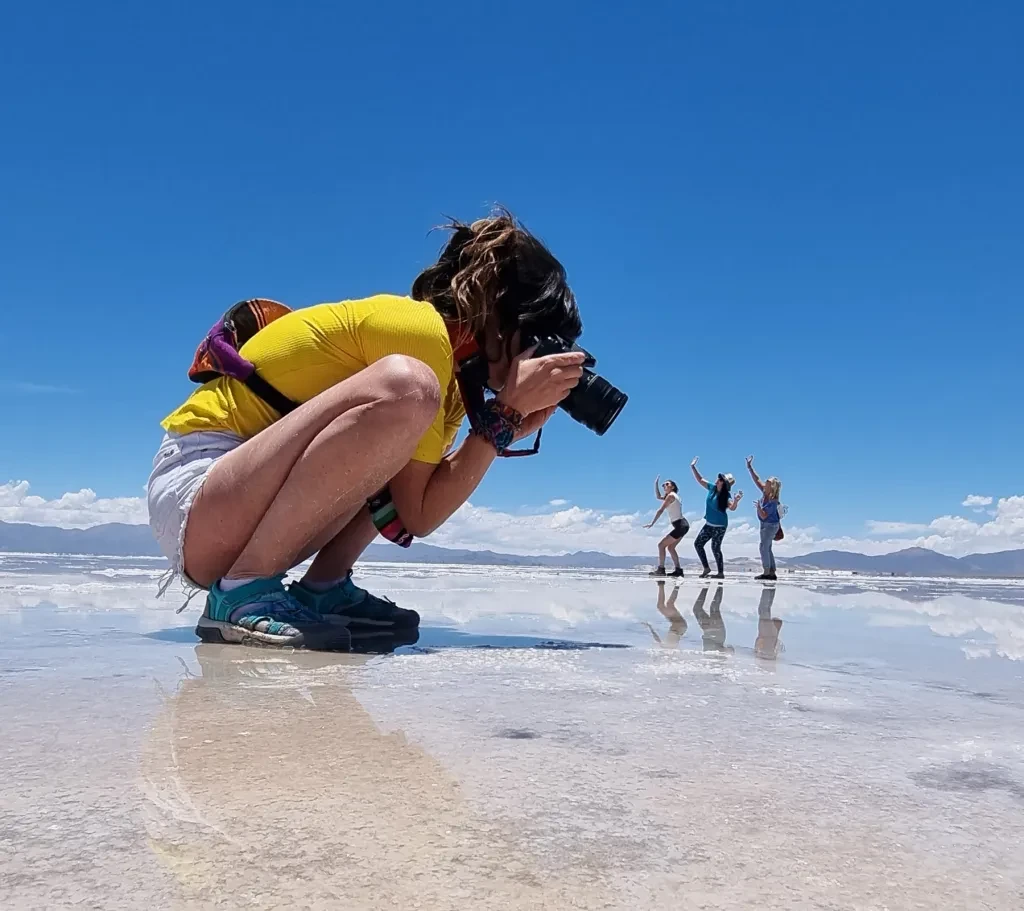 Persona sacando fotos sobre la superficie espejada de las Salinas Grandes